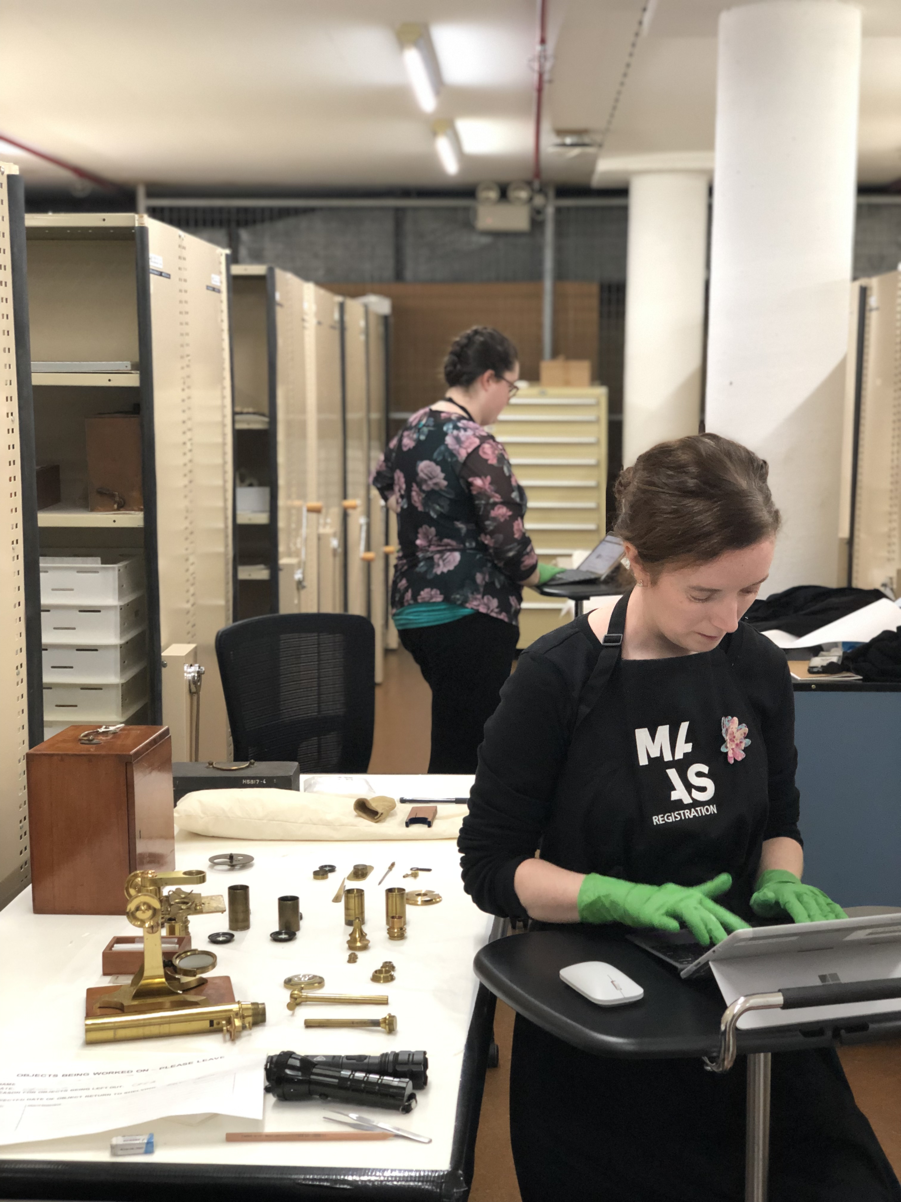 Conservator Megan Hall and Registrar Kate Clancy from the Assessment Team at work in the collection store entering information into the EMu collection database on their laptops.